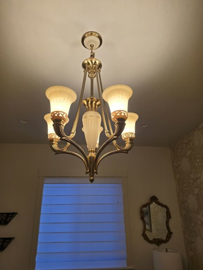 Classic vintage chandelier with six frosted glass shades in warm light