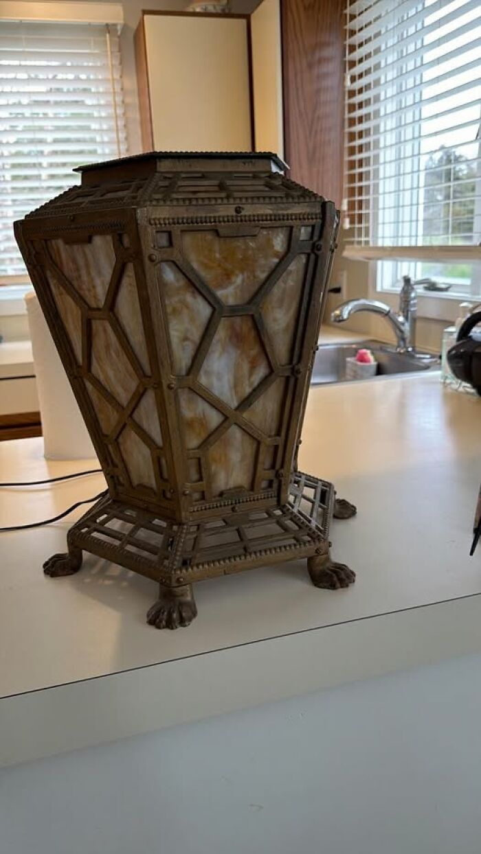 Vintage secondhand lamp with geometric stained glass and metal claw feet on surface