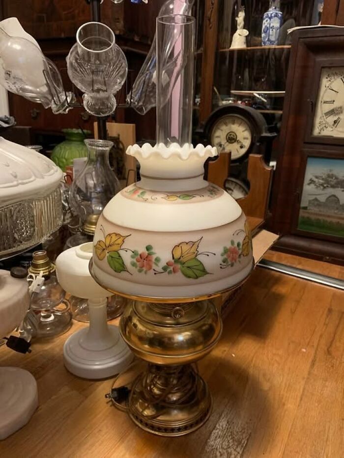 Vintage floral-patterned glass lamp with brass base displayed among antiques