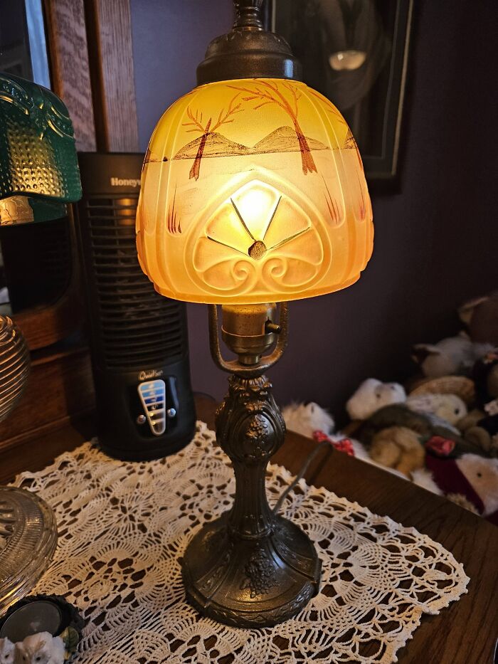 Antique vintage lamp with warm amber painted glass shade and ornate metal stand