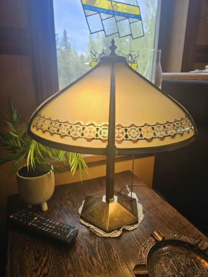 Vintage secondhand lamp with stained glass shade on wooden table near window