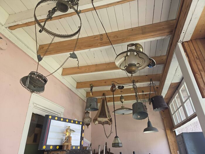Hanging vintage secondhand lamps with various metal and glass designs on wooden ceiling beams
