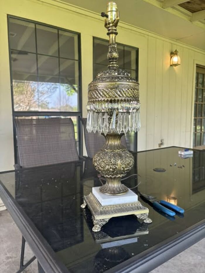 Intricately designed vintage brass lamp with crystal drops sitting on glass table