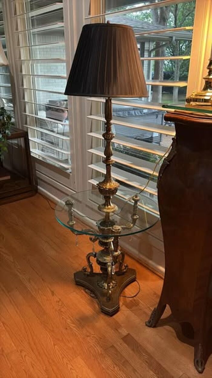 Tall brass vintage floor lamp with black pleated shade beside window blinds