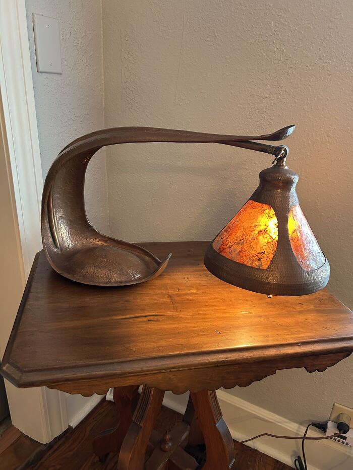 Unique vintage metal desk lamp with amber stained-glass shade on wooden table