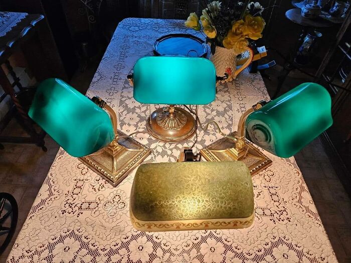 Set of vintage secondhand bankers lamps with green shades on lace table