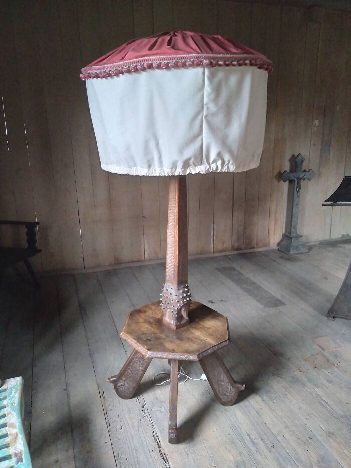 Vintage secondhand wooden floor lamp with pink and white fabric shade in rustic room