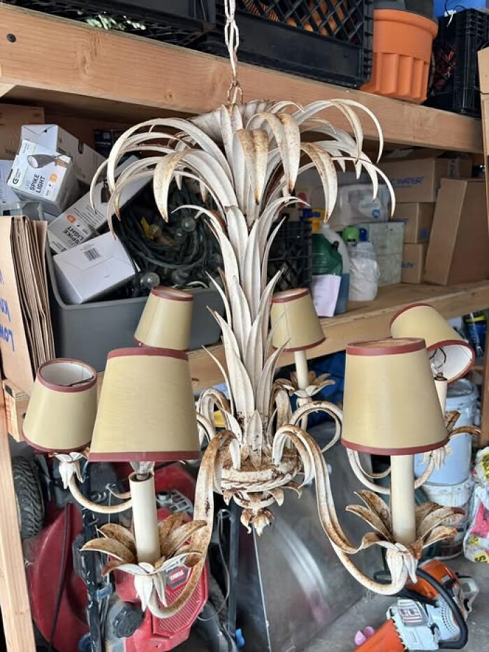 Rustic vintage secondhand metal chandelier with small lampshades hanging in garage