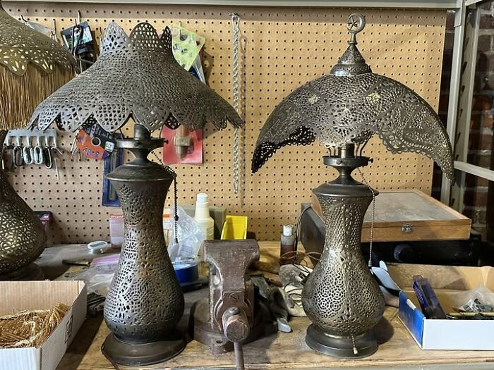 Pair of vintage secondhand lamps with intricate pierced metal shades on a workbench