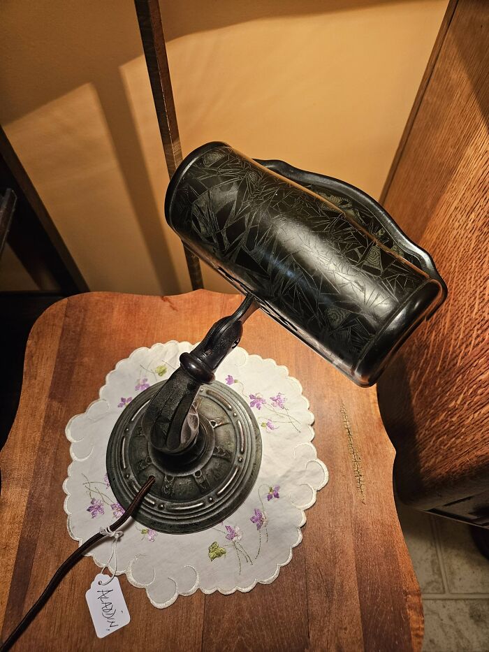 Black vintage desk lamp with engraved floral patterns on wooden table