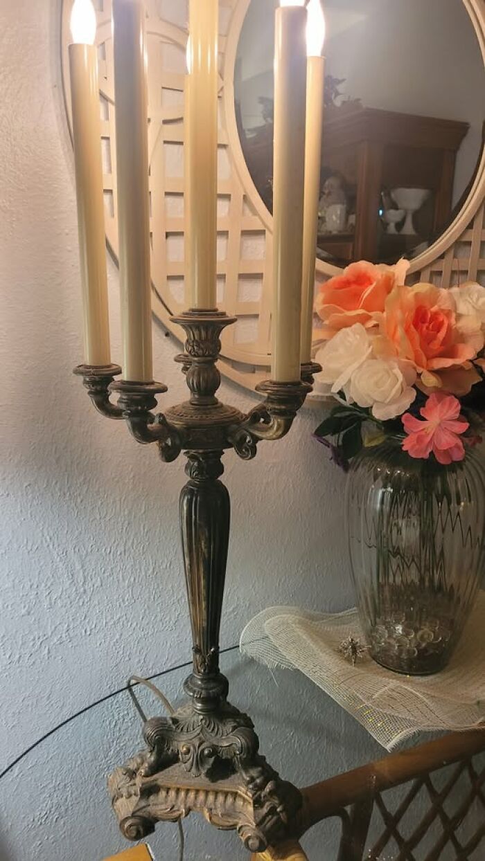 Ornate vintage secondhand candelabra lamp with four candle-shaped bulbs near flowers