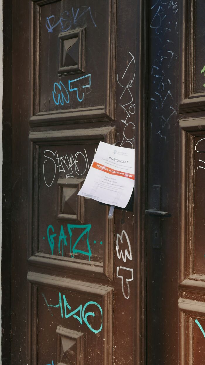 Graffiti-covered door with water supply notice taped, neighbors from hell situations