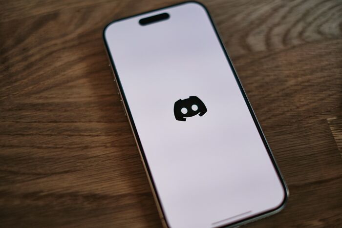 Smartphone displaying Discord app loading screen on wooden table