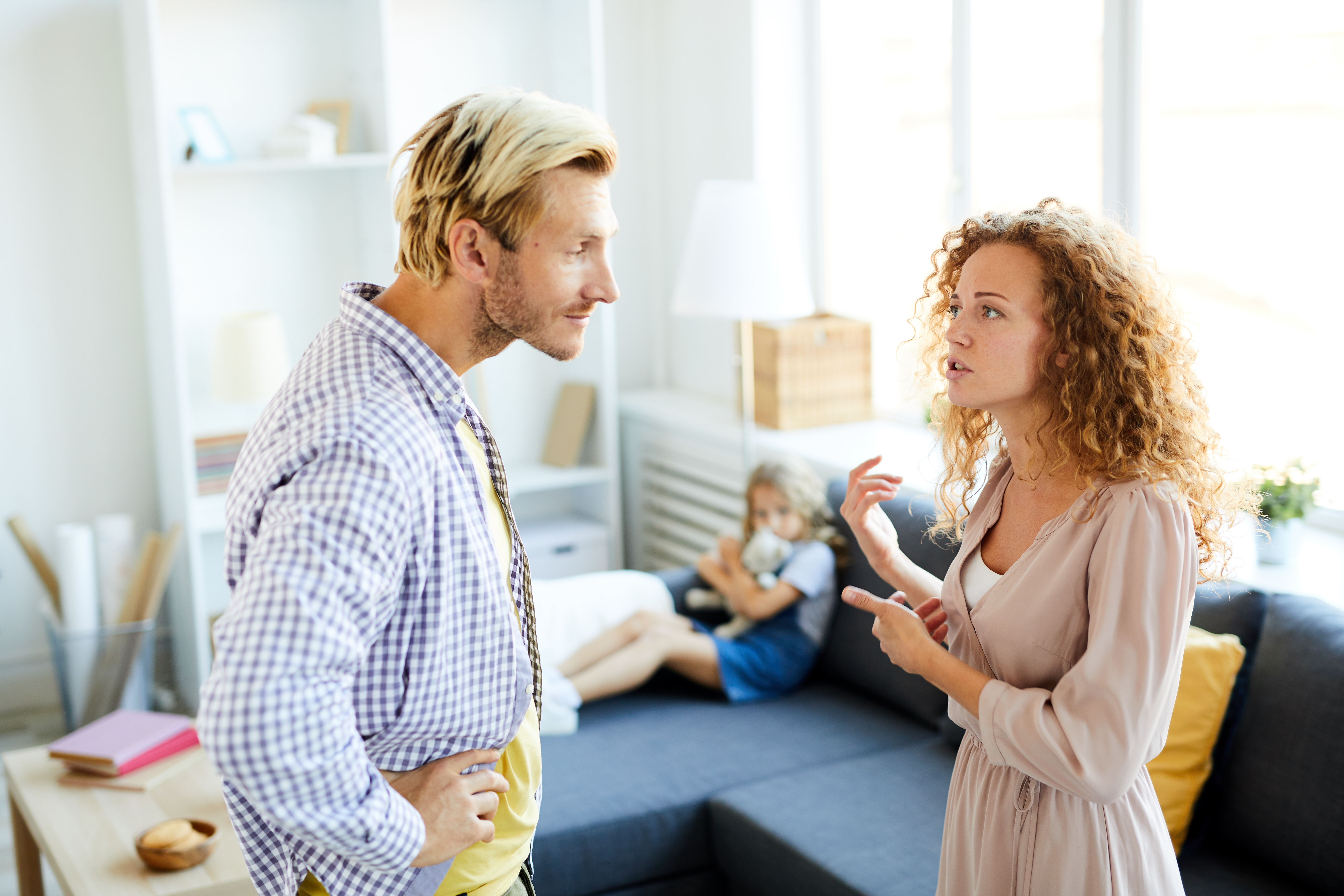 Couple arguing indoors with child in background illustrating family dispute over support