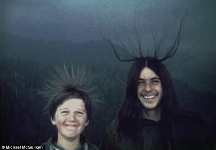 Two smiling boys with static hair against a dark background strange bench photo