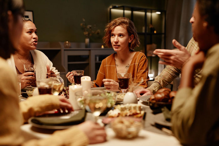 Woman at dinner looking upset during family conversation about babysitting Woman at dinner looking upset during family conversation about babysitting