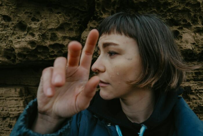 Side profile of a person with short hair touching hand near rocks terrifying experience