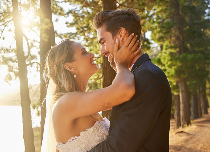Wedding couple embracing happily outdoors in a forest setting Wedding couple embracing happily outdoors in a forest setting