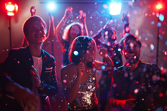 Group of people enjoying a celebration party with confetti and colorful lights