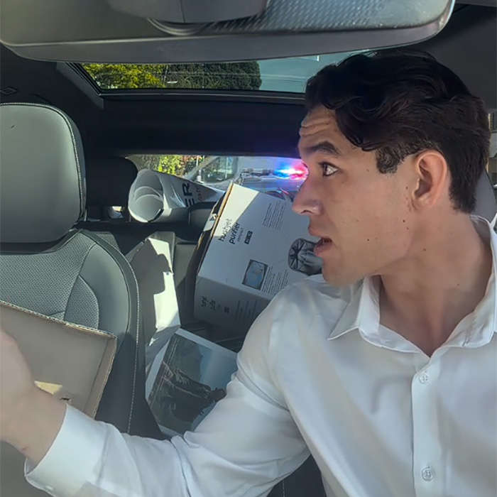 Man looking back inside car with police lights visible