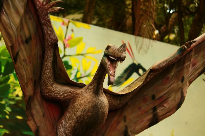 Realistic dinosaur model with open mouth in outdoor setting