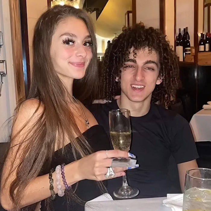 Mackenzie Shirilla with man smiling at dinner holding champagne glass