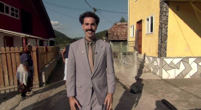 Borat smiles in a light grey suit, an image sure to inspire hilarious engagement stories.