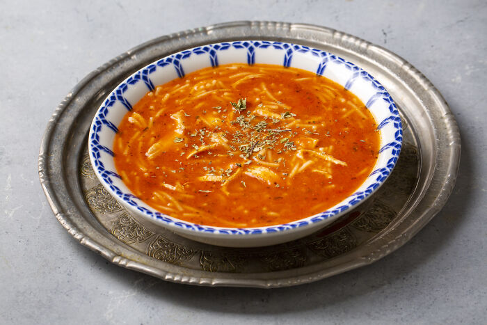 Tomato soup with noodles served in a patterned bowl as an affordable poverty meal