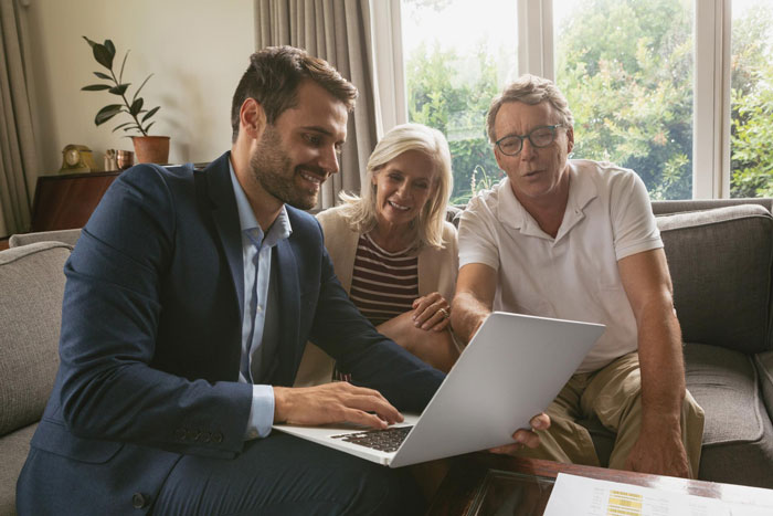Couple reviewing finances with wealth advisor showing laptop screen Couple reviewing finances with wealth advisor showing laptop screen