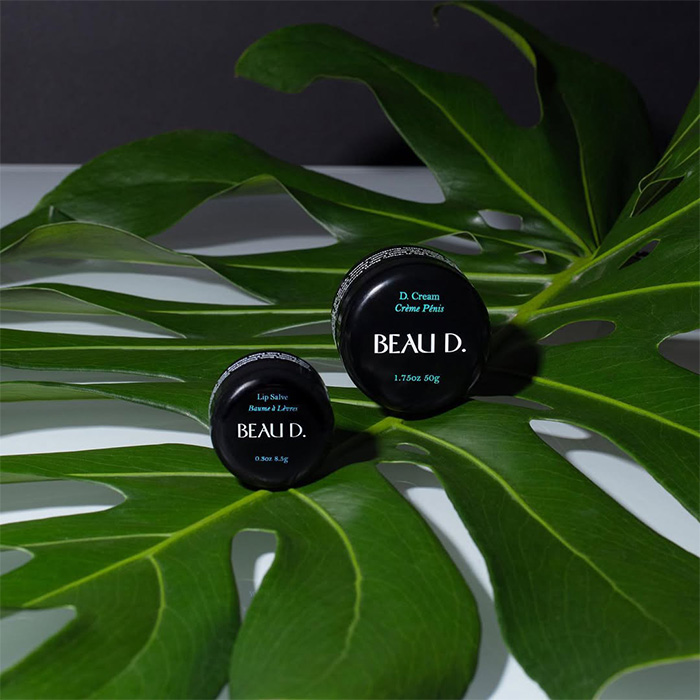 Beau D. private parts cream and lip salve containers on green leaf