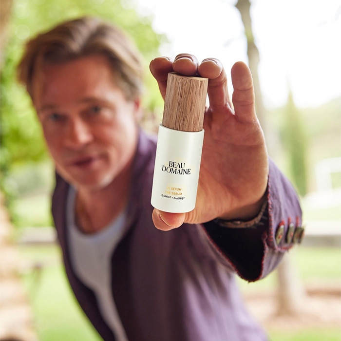 Brad Pitt holding Beau Domaine serum bottle close to camera