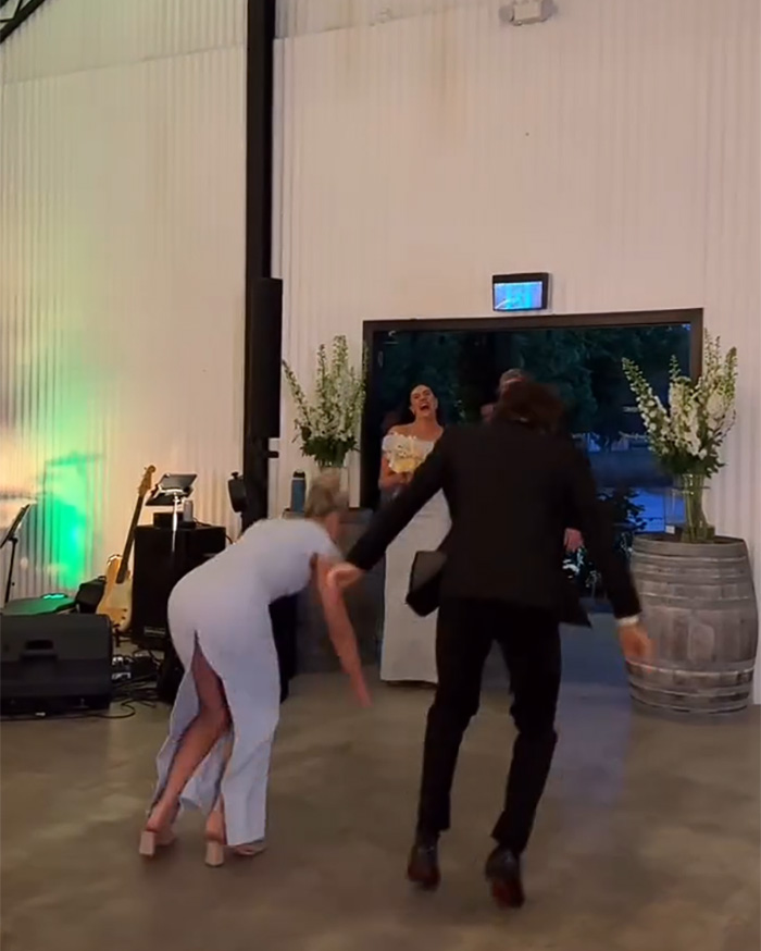 Bridesmaid and partner dancing as bride reacts to wedding dance mishap