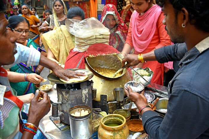 Indian street food vendor serves locals, showcasing daily life abroad. Avoid annoying things tourists do by observing local culture.