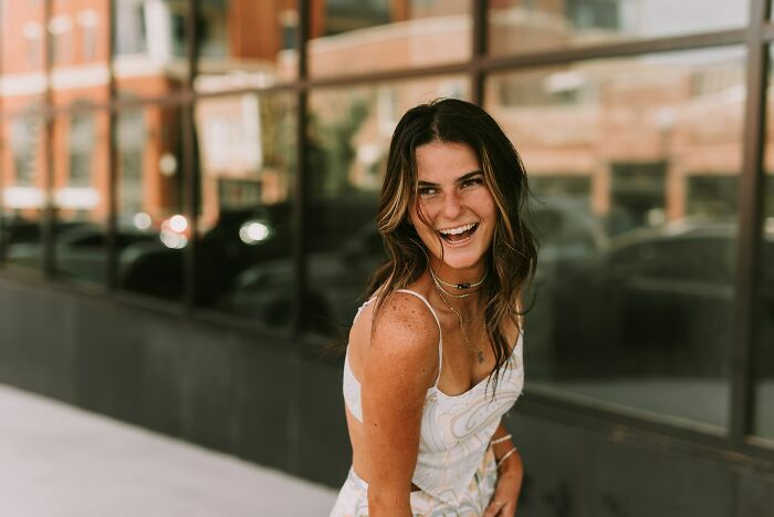 Joyful woman smiling outdoors, showcasing a moment of silent luxury.