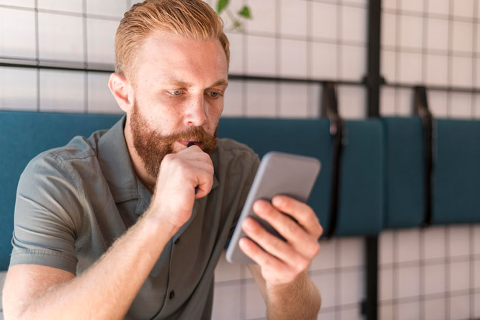 Worried man looking at smartphone showing tension in family over newborn Worried man looking at smartphone showing tension in family over newborn