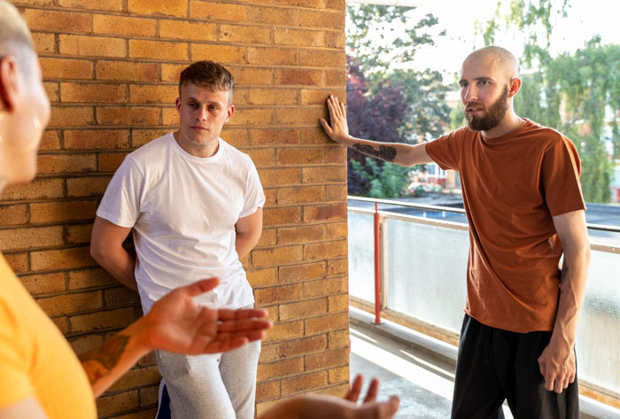 Two men having a serious conversation on a balcony involving bullying issues
