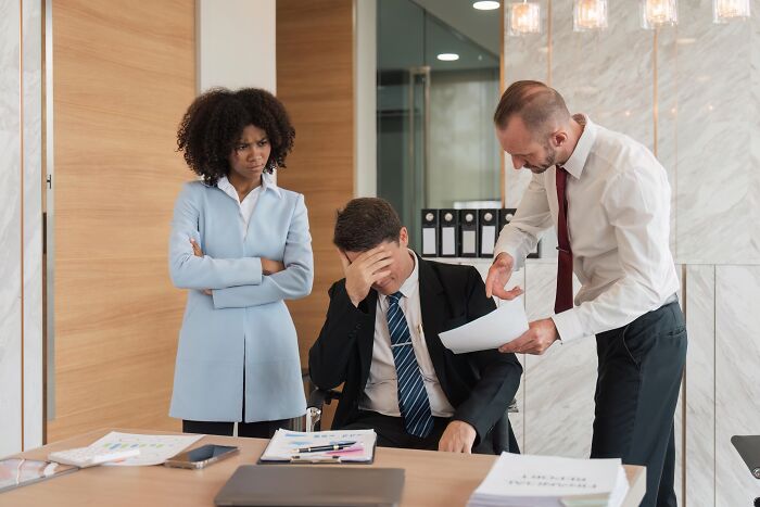 Stressed employee covering face while being scolded at work