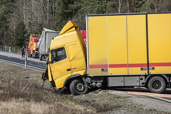 A yellow truck crashed into a ditch, its cab severely damaged. Another tow truck is seen behind it. Very creepy things.