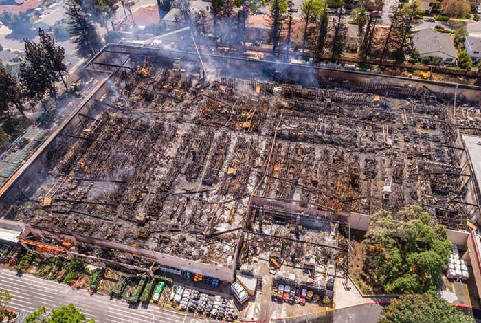 Aerial view of a large commercial building completely destroyed by fire, an example of catastrophic failure.