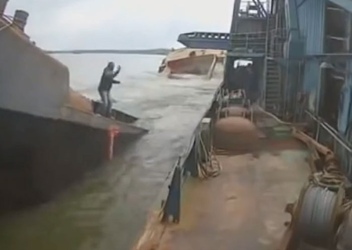 A boat capsizes next to another vessel, machinery failing catastrophically, as a man stands on the sinking deck.