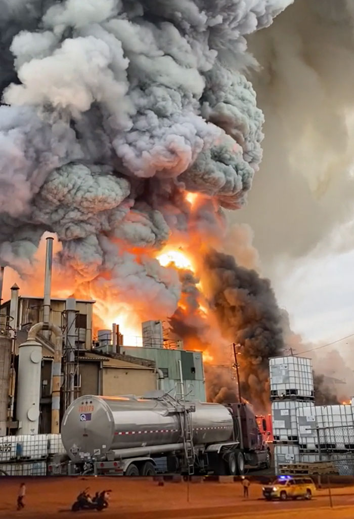 Massive industrial fire with thick black smoke and orange flames engulfing a machinery structure, a catastrophic failure.