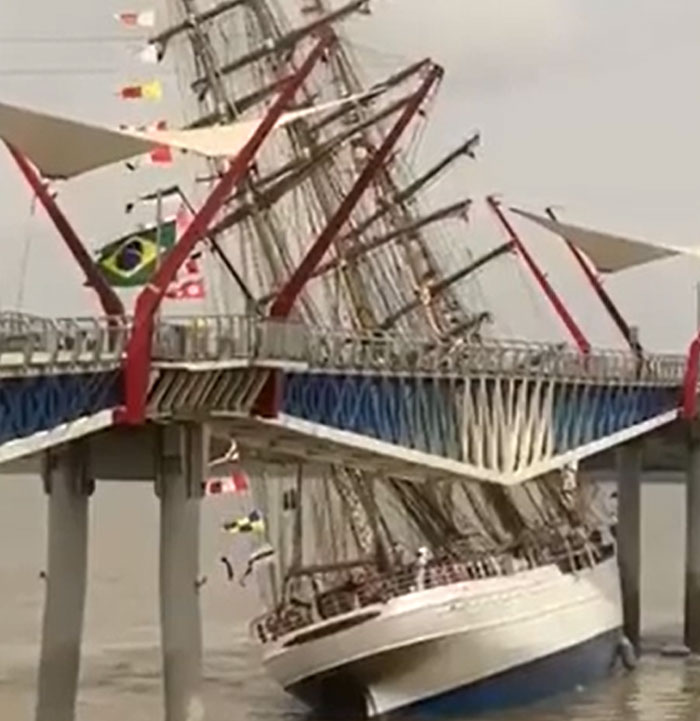 A tall ship attempting to pass under a bridge, machinery failing catastrophically and hitting the structure.