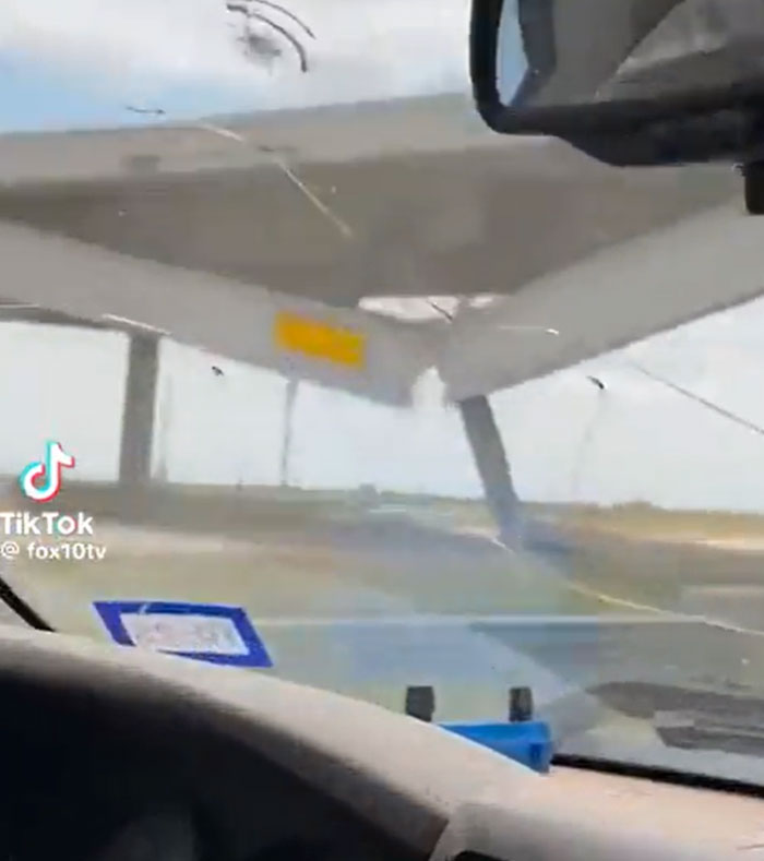 View from inside a car of a machinery failure, showing a light aircraft with a propeller bent or snapped, indicating catastrophic damage.