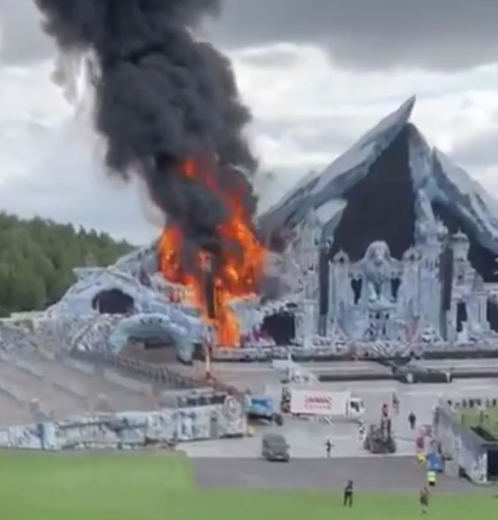 A large stage structure, resembling icy mountains, with a section engulfed in catastrophic machinery failure and flames.