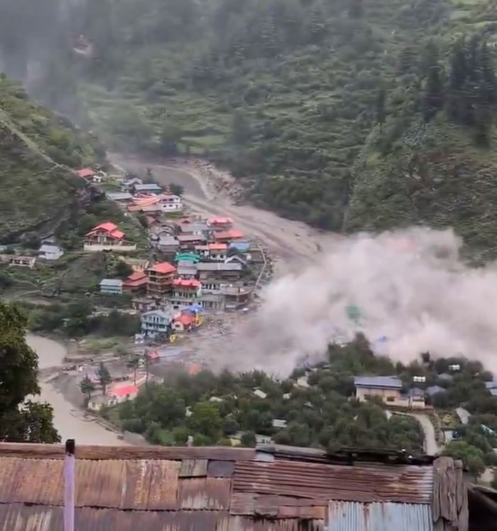 Village by a river, engulfed in a massive dust cloud from a catastrophic landslide, showcasing failed structures.