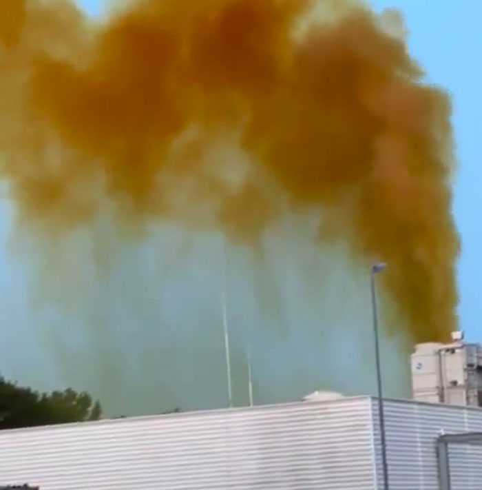 Catastrophically failed industrial machinery emitting thick brown smoke against a blue sky.