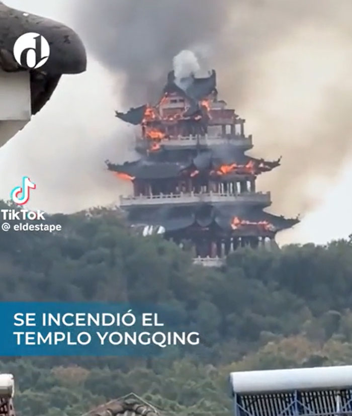 The Yongqing Temple structure on a hill, engulfed in flames and smoke, showing a catastrophic failure.