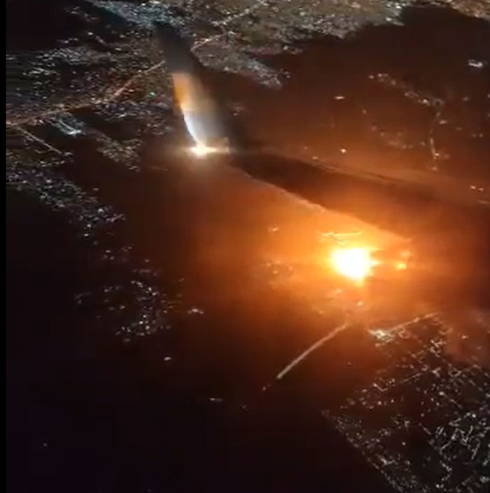 Aerial view of a bright explosion, possibly a machinery or structure that failed catastrophically, illuminating a dark landscape.