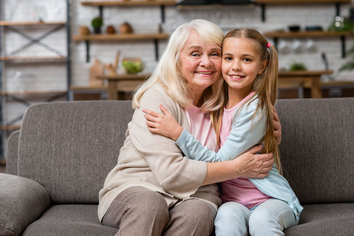 Grandmother hugging granddaughter on couch smiling Grandmother hugging granddaughter on couch smiling