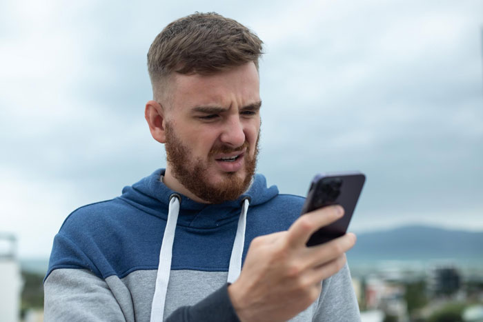 Concerned man looking at phone with worried expression Concerned man looking at phone with worried expression